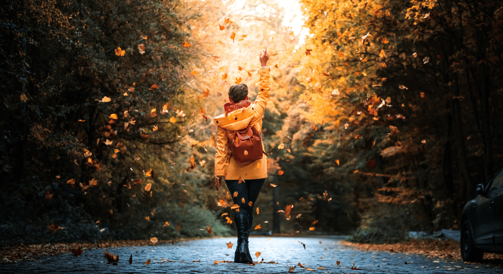 a woman walking down a road in the fall