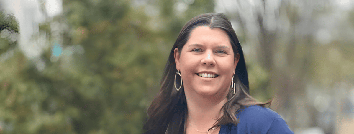 Whitney B. Altizer, smiling outdoors with blurred greenery in the background.