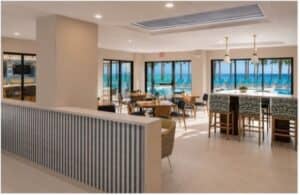 An airy hotel dining room with tables, chairs, and large glass doors